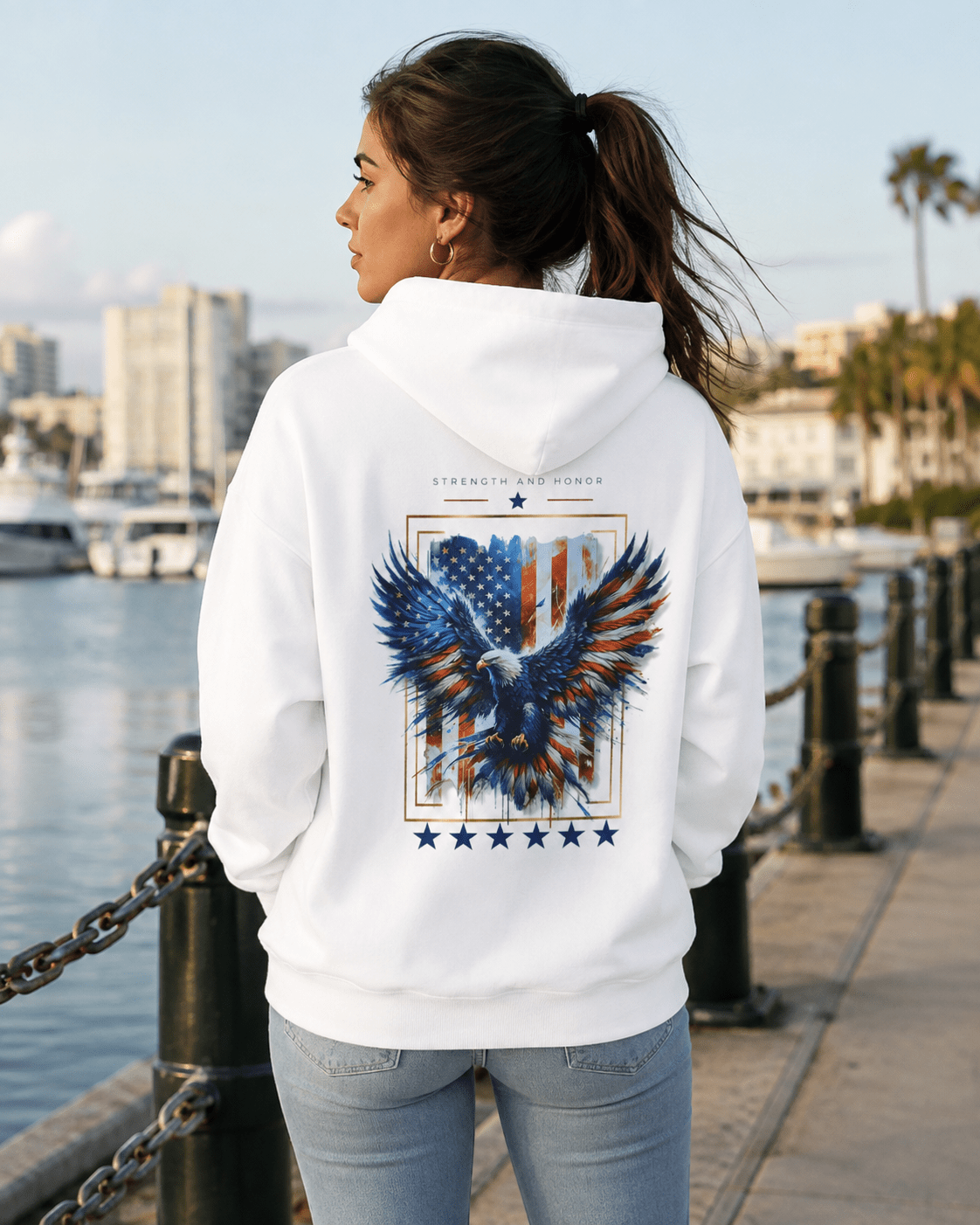 White hoodie worn by woman, back eagle and stars graphic visible over the shoulder
