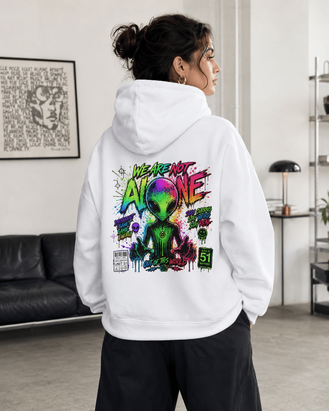 White hoodie worn from behind indoors, with colorful alien graphic on the back