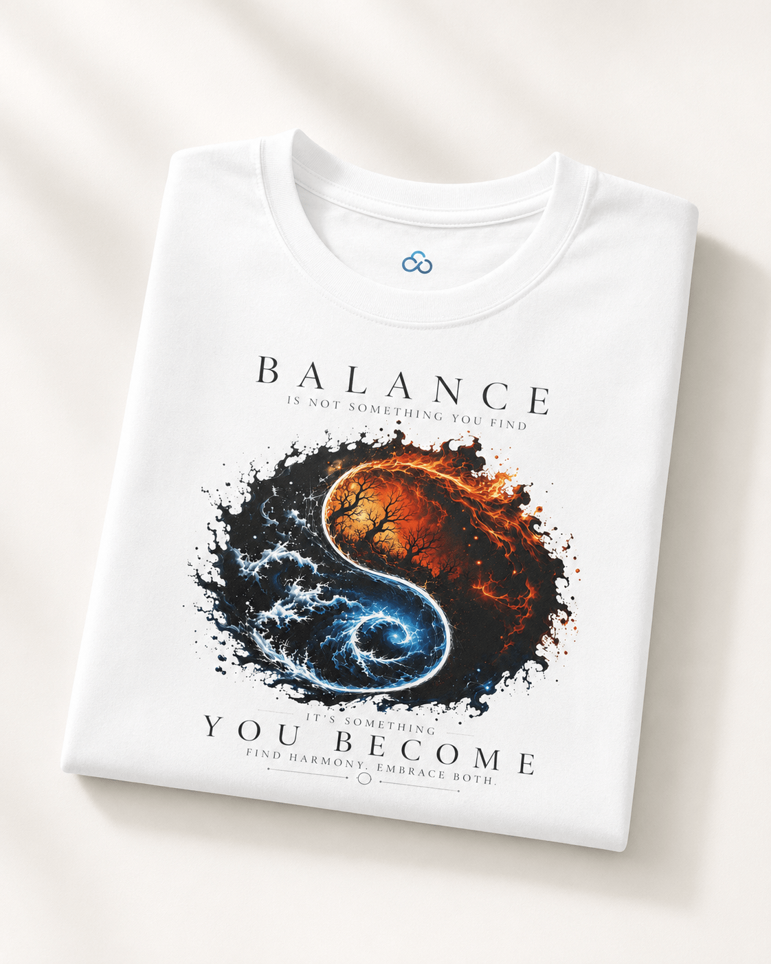 A folded white t-shirt with a graphic print of a yin-yang symbol made from a fiery orange-red spiral and a blue-white spiral, with the text 'BALANCE IS NOT SOMETHING YOU FIND.