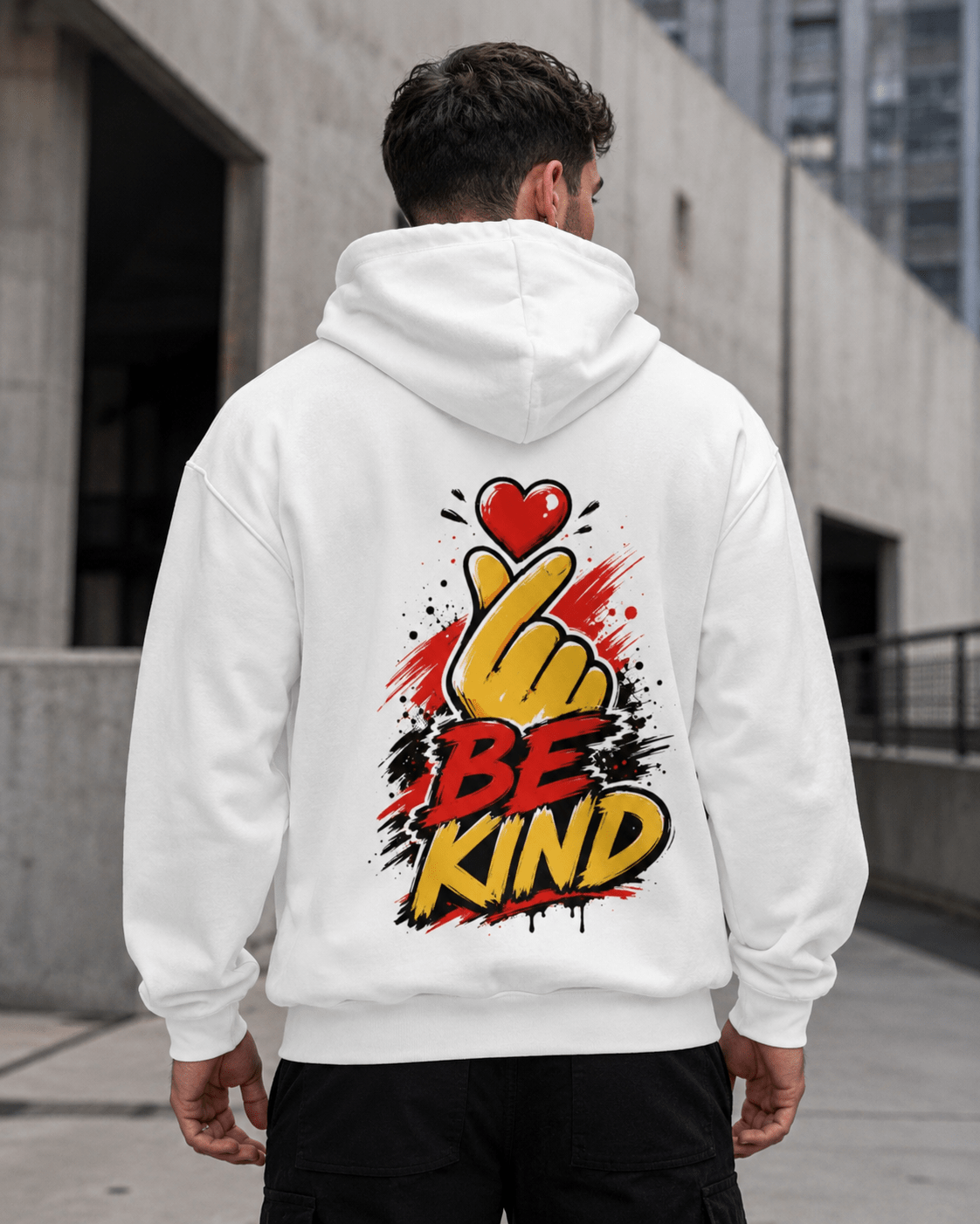 White hoodie worn from behind with centered 'Be Kind' heart-and-hand graphic