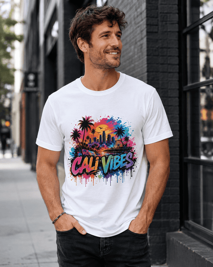 A man wearing a white crewneck t-shirt with a colorful 'Cali Vibes' graphic print featuring palm trees and a city skyline, standing on a city sidewalk.