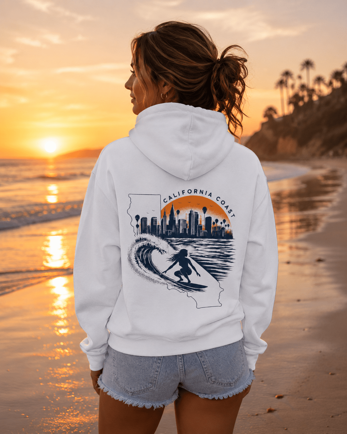 White hoodie worn from behind; California coast surf and city skyline graphic