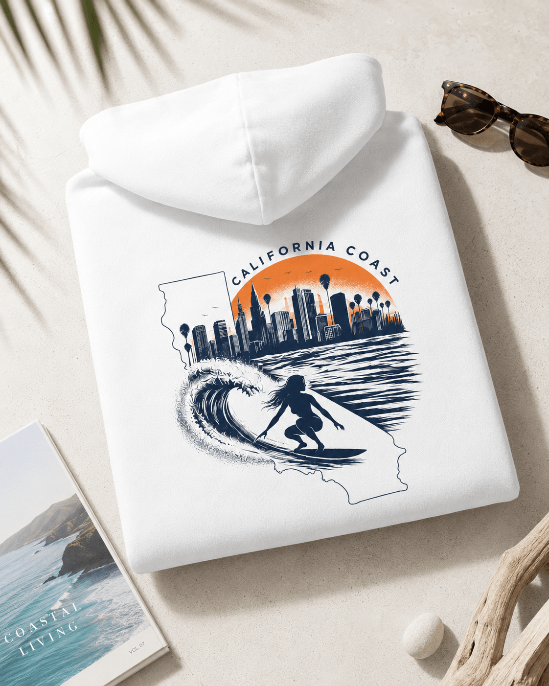 Folded white hoodie with hood; surfboard and city skyline graphic on back