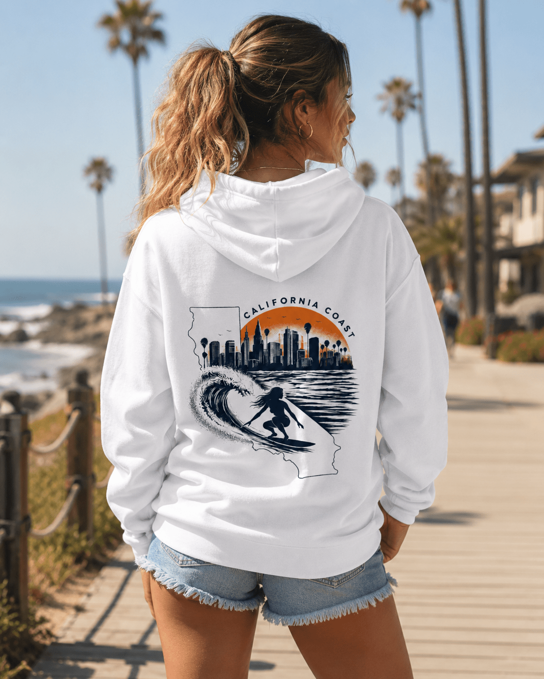 White hoodie worn from behind; California coast surf city skyline graphic