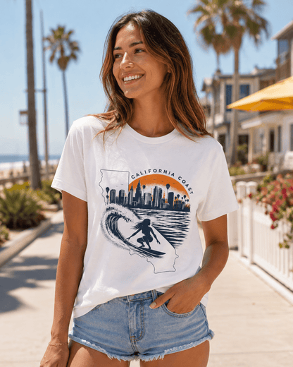 White graphic T-shirt featuring California coast skyline and wave surfer print, worn