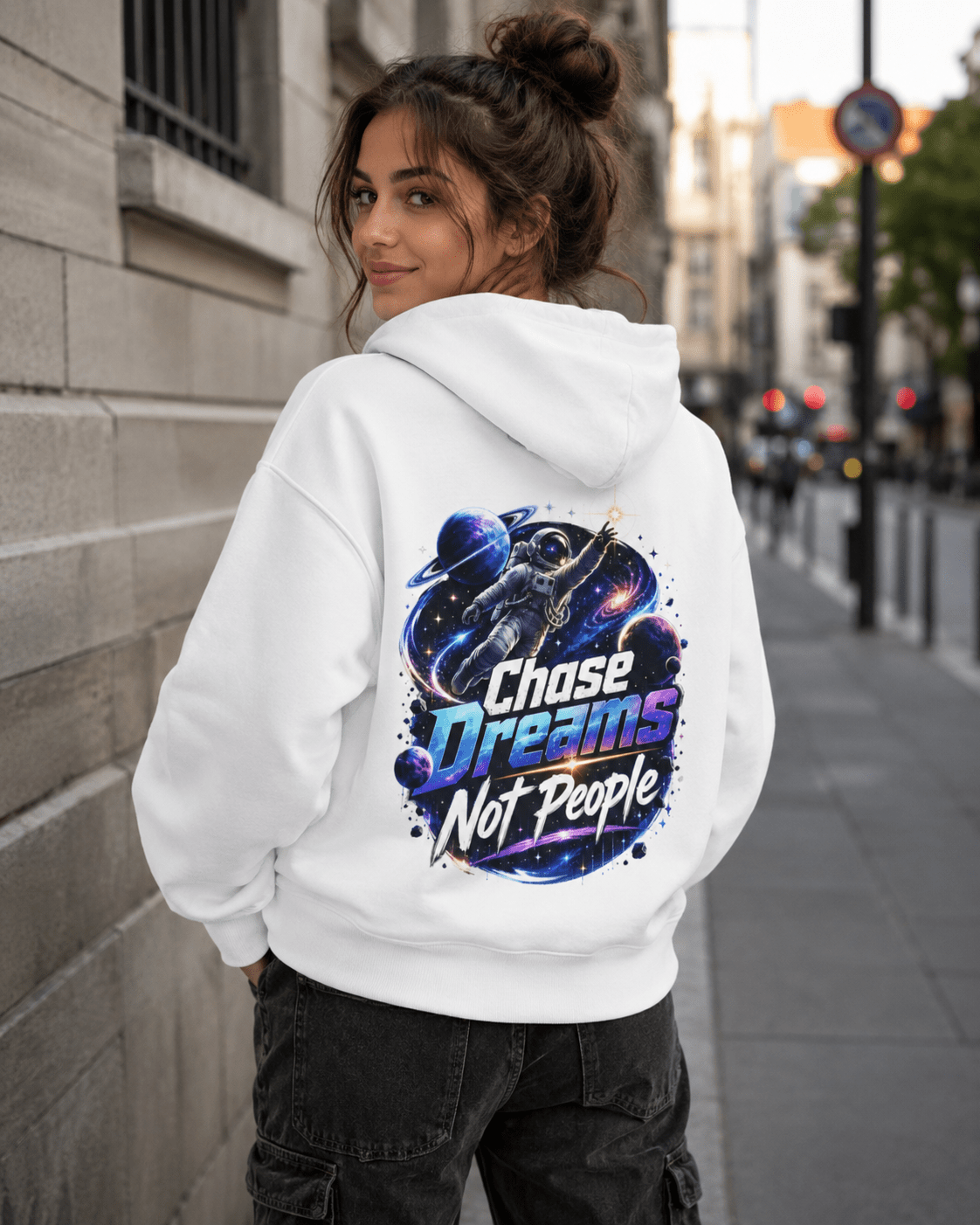 White pullover hoodie worn by woman, back astronaut graphic with colorful text
