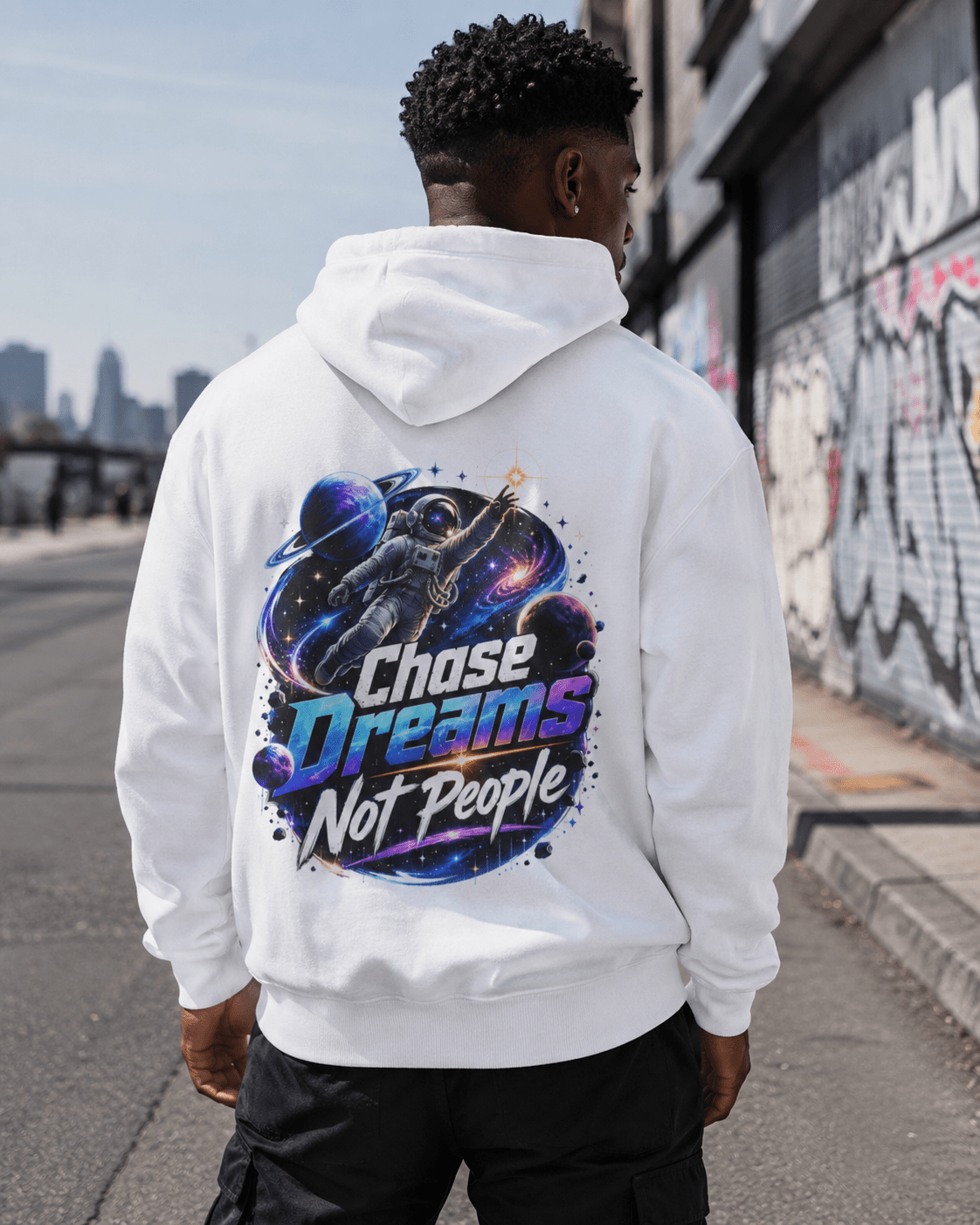 White pullover hoodie worn by man, back astronaut graphic with colorful text
