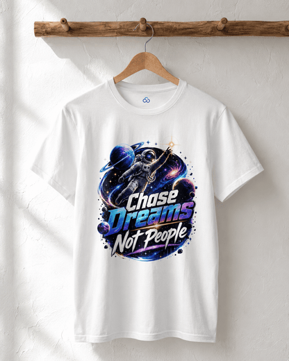 White crewneck T-shirt hanging on wooden hanger, astronaut “Chase Dreams Not People” chest graphic.