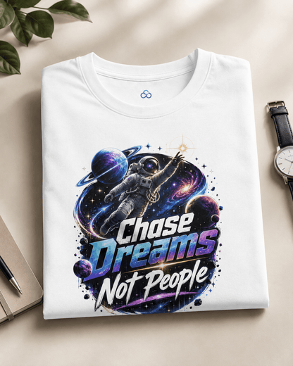 White graphic T-shirt folded flat, astronaut “Chase Dreams Not People” print centered on chest.