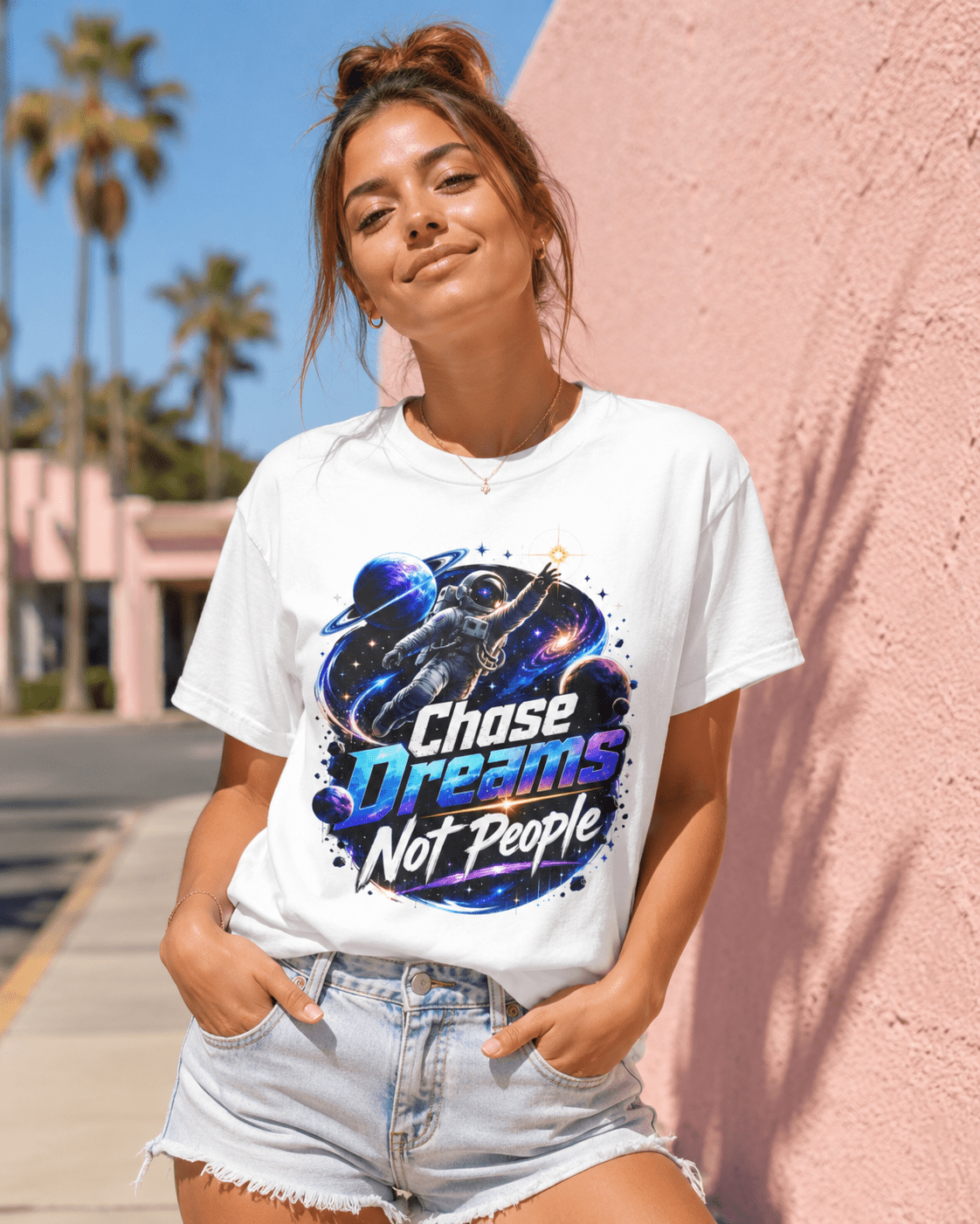 White crewneck T-shirt on person, astronaut “Chase Dreams Not People” graphic at center front.