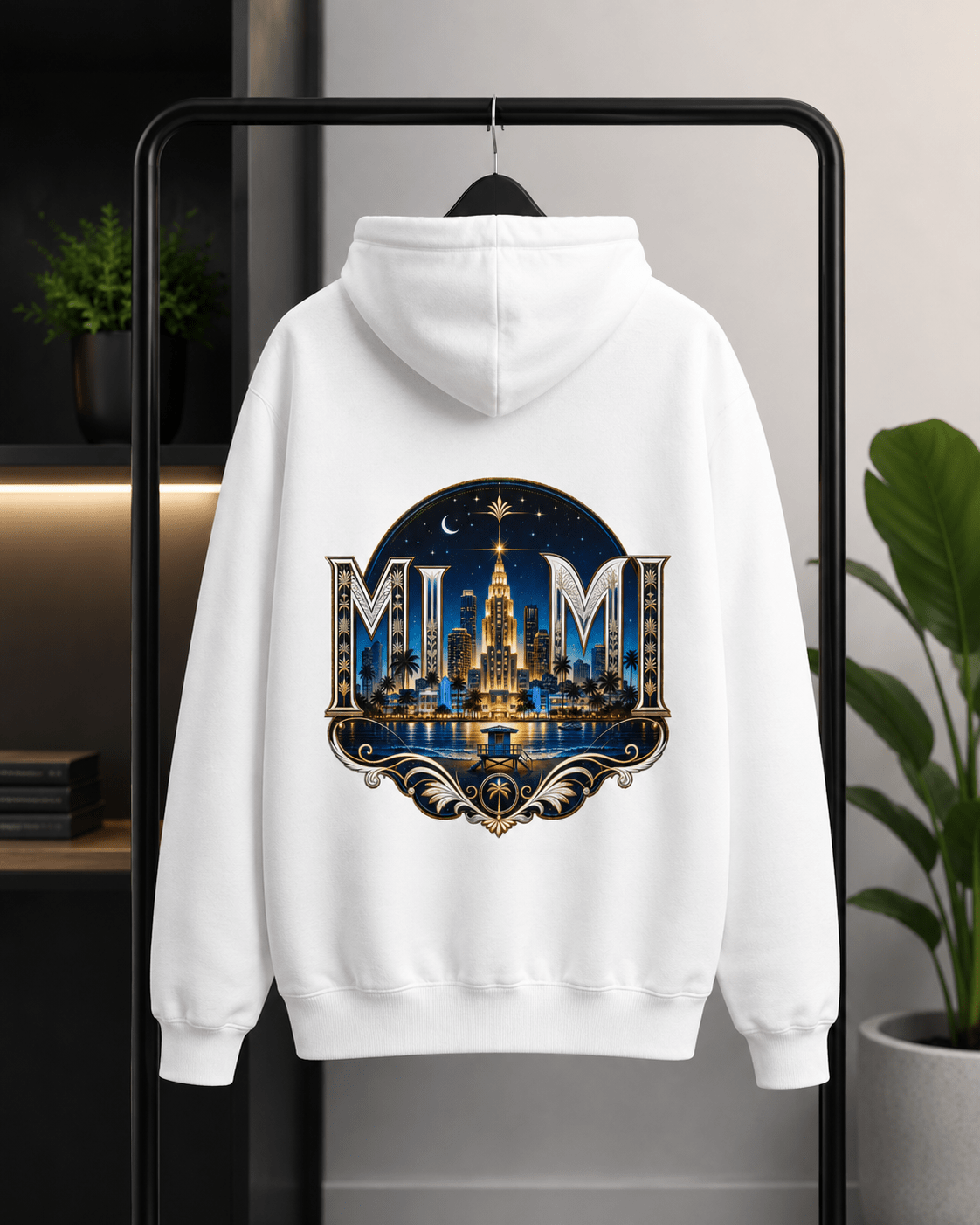 A white pullover hoodie hanging on a black clothing rack, featuring a large circular graphic on the back with the word 'MUM' in ornate lettering above a glowing cityscape and fountain design.
