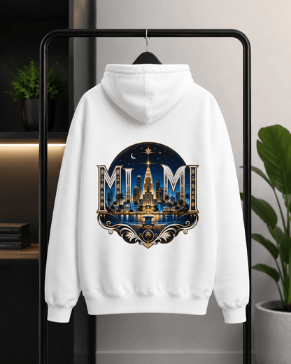 A white pullover hoodie hanging on a black clothing rack, featuring a large circular graphic on the back with the word 'MUM' in ornate lettering above a glowing cityscape and fountain design.