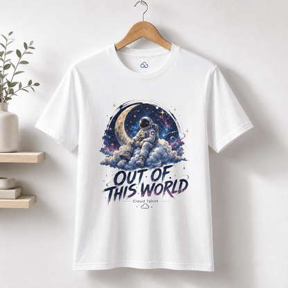A white short-sleeve graphic T-shirt hanging on a wooden hanger against a light wall. The shirt features a colorful space-themed print with an astronaut sitting on clouds in front of a crescent moon and stars, with the text 'OUT OF THIS WORLD' and a small 'Cloud Native' logo below.