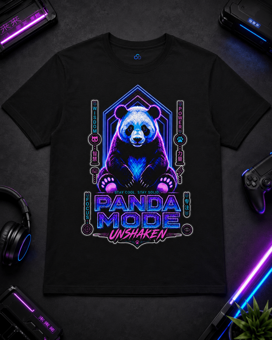 A black short-sleeve graphic T-shirt laid flat on a dark surface, surrounded by gaming-themed props including a controller, headphones, a neon light, and a small plant. The shirt features a large neon-style panda illustration with the text 'PANDA MODE UNSHAKEN' in glowing blue, purple, and pink tones.