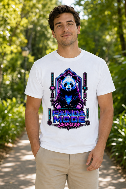A man wearing a white graphic t-shirt with a colorful 'PANDA MODE UNSHAKEN' design featuring a panda bear, standing on a sunlit path surrounded by green foliage.