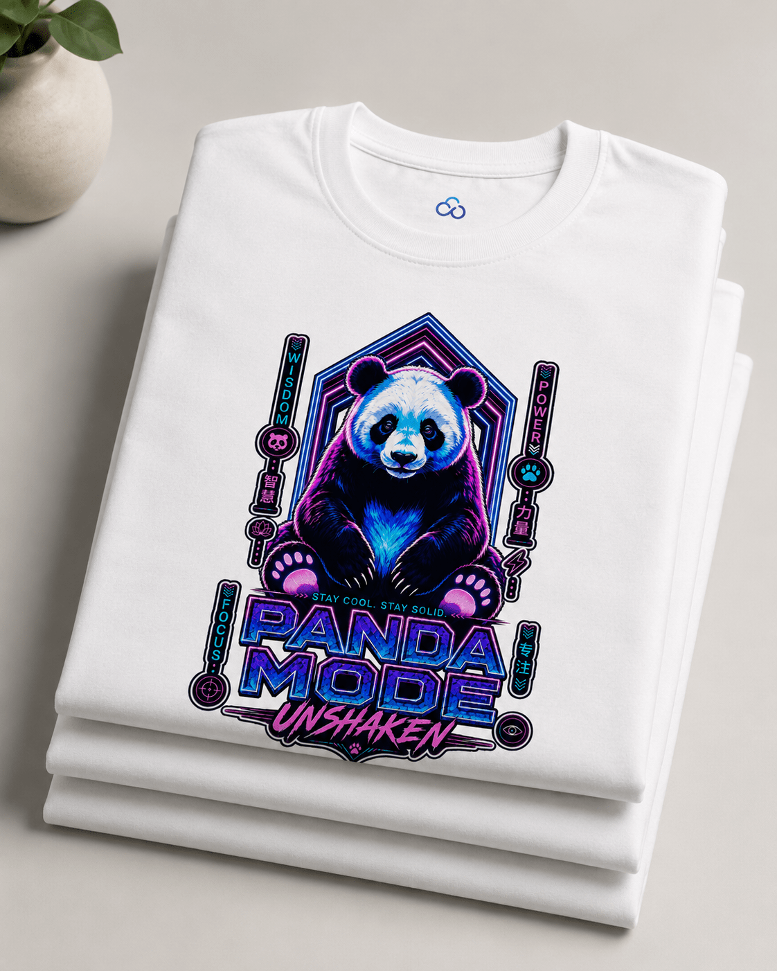 A folded white crewneck t-shirt with a colorful graphic of a panda bear and the text 'PANDA MODE UNSHAKEN' in a neon purple and blue style, displayed on a light gray surface.