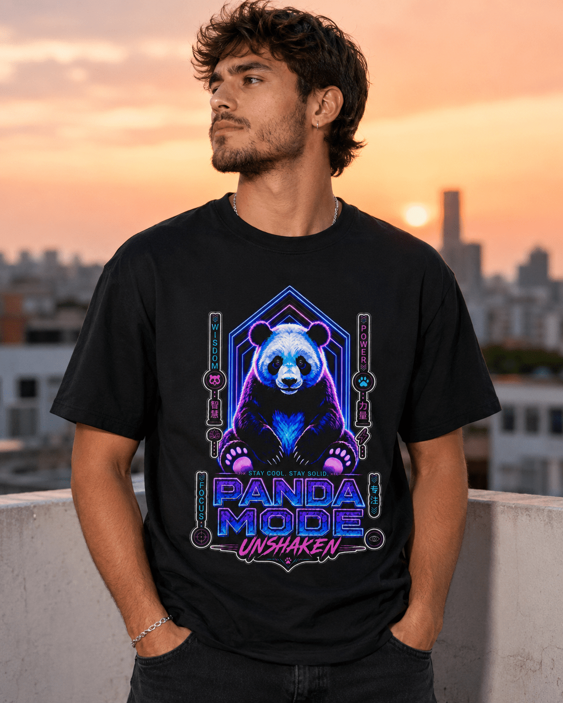 A man wearing a black graphic t-shirt with a neon panda design and the text 'PANDA MODE UNSHAKEN' stands on a rooftop at sunset.
