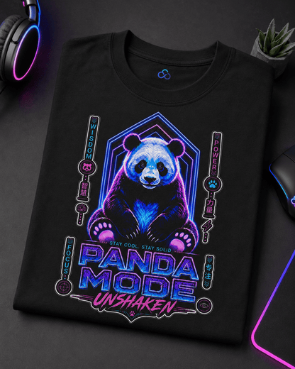 A black short-sleeve t-shirt with a colorful graphic of a panda bear and the text 'PANDA MODE UNSHAKEN' in neon blue and pink, displayed on a dark desk with gaming accessories.