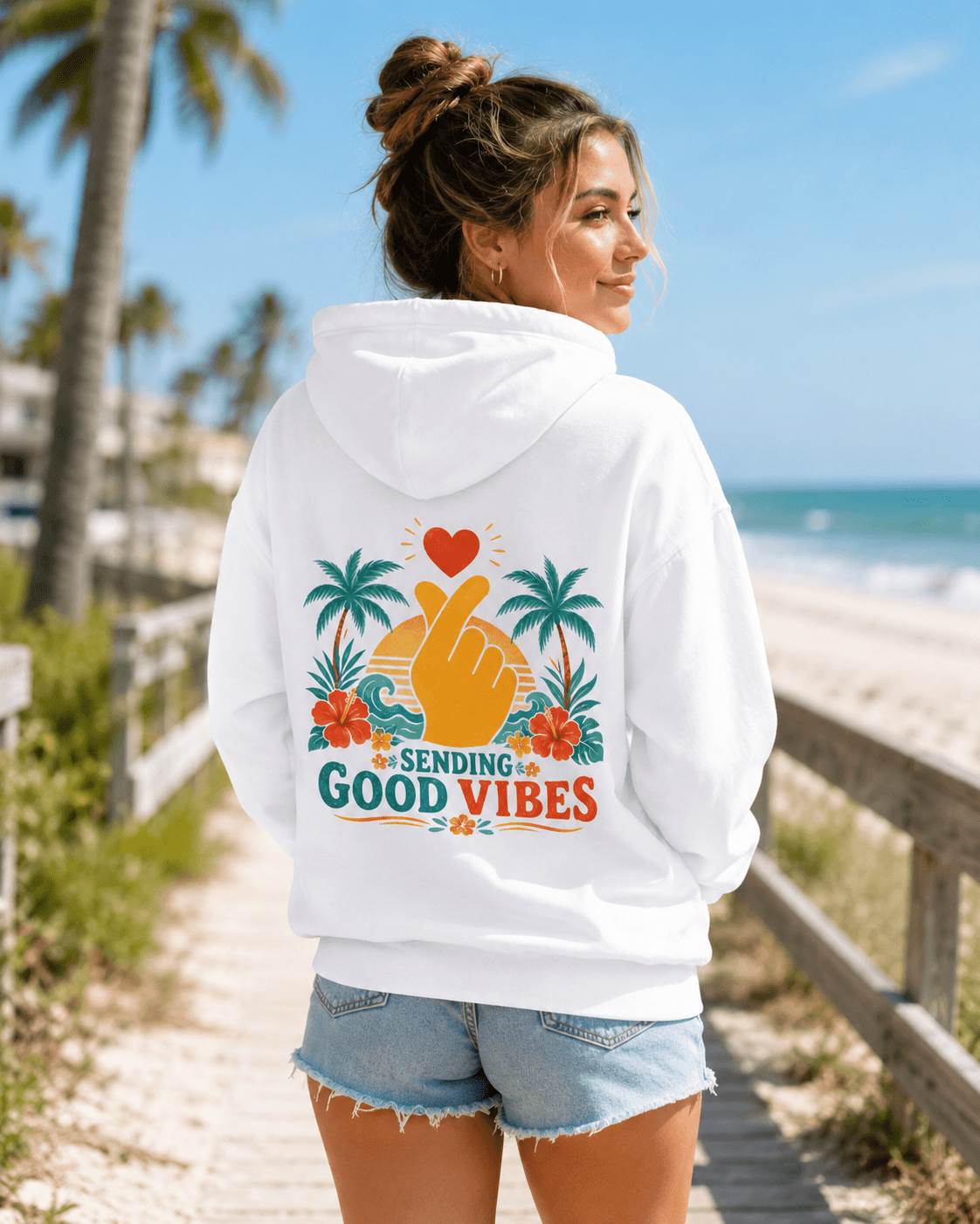 White hoodie with hood and back Good Vibes palm-heart graphic, worn with jeans