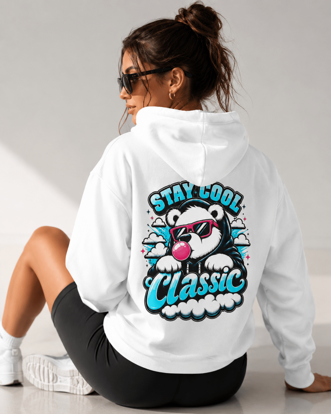 White hoodie with bear graphic and 'Stay Cool Classic' text on back, seated