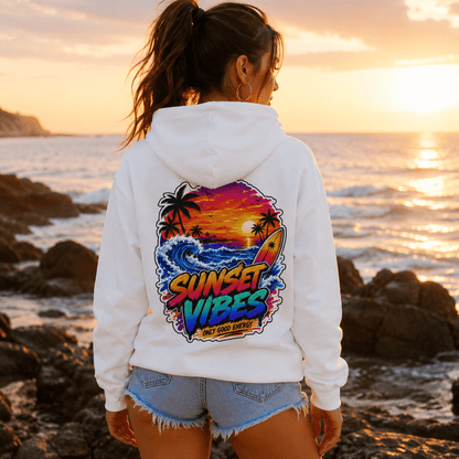 White hoodie with back sunset graphic, woman wearing it by the ocean