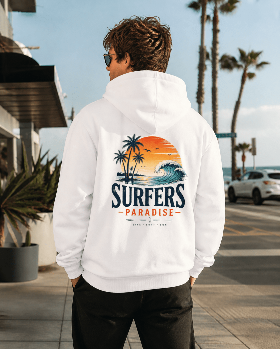 White pullover hoodie on person; hood up, surf-themed back print with palms and wave