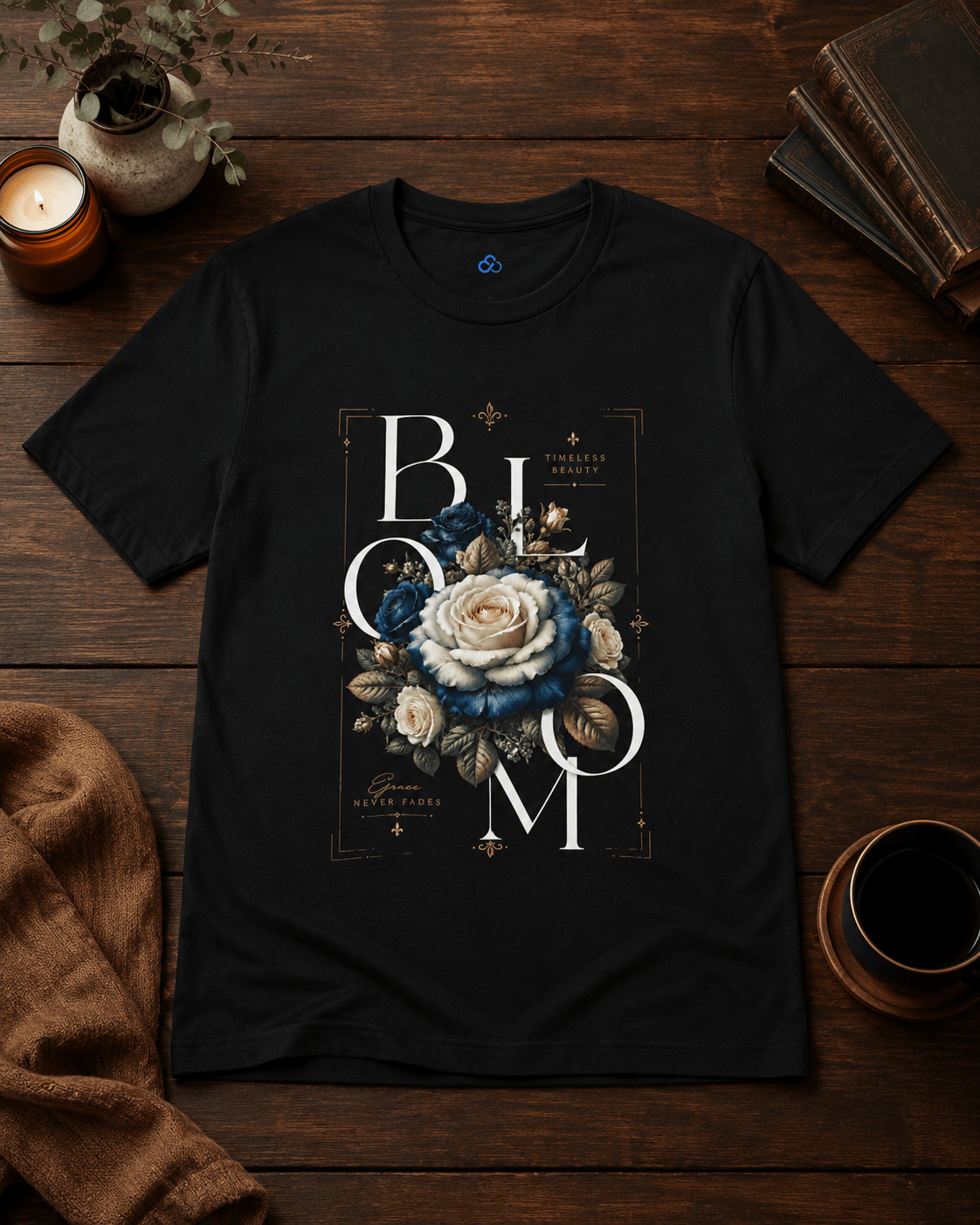 Black t-shirt with floral design and 'BLOOM' text on a wooden surface with candles and books.