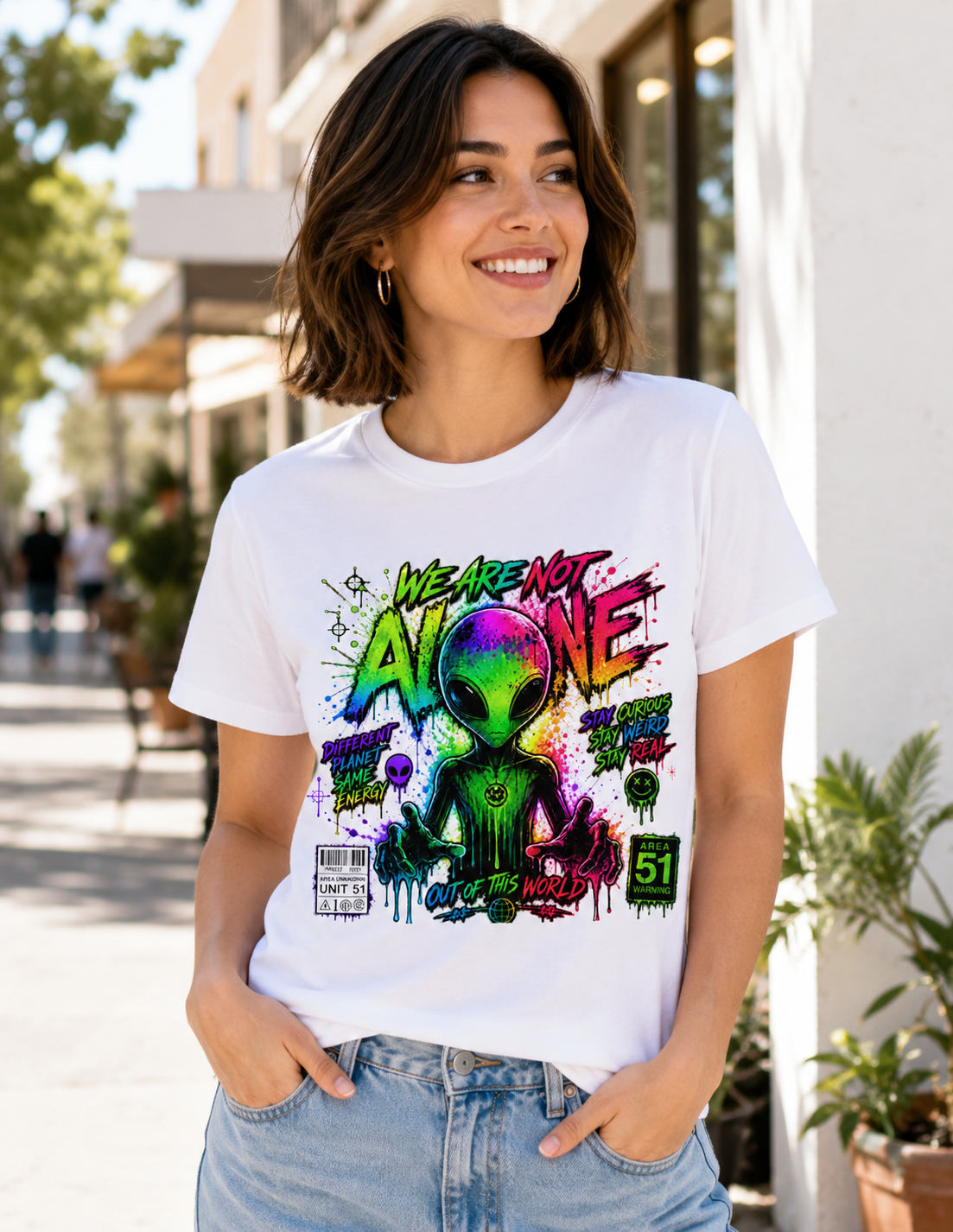 White graphic T-shirt worn by woman, alien head and colorful front artwork